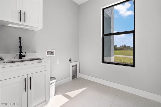 clothes washing area featuring cabinets, light tile patterned floors, hookup for a washing machine, electric dryer hookup, and sink