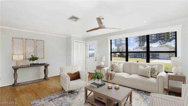 living room featuring ceiling fan, ornamental molding, and light hardwood / wood-style flooring