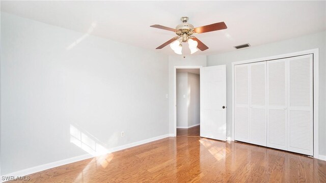 unfurnished bedroom with hardwood / wood-style floors, ceiling fan, and a closet