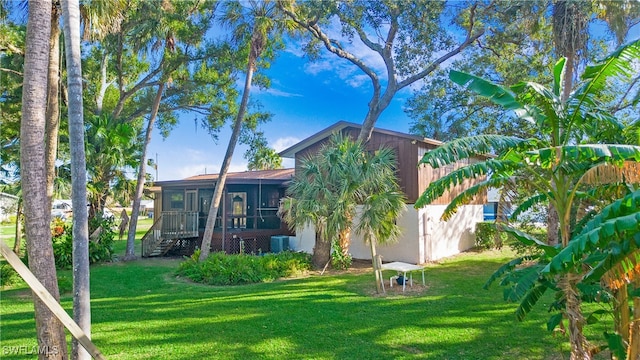 rear view of property with a sunroom, central AC, and a yard