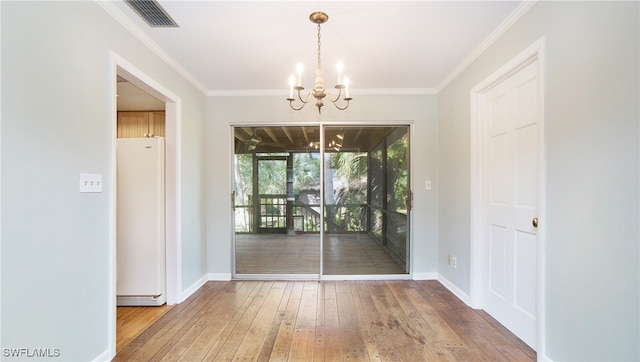 unfurnished dining area featuring hardwood / wood-style floors, a chandelier, and crown molding