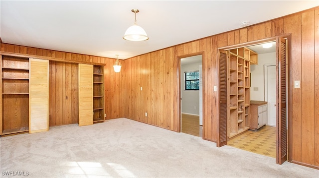 unfurnished bedroom featuring carpet and wood walls