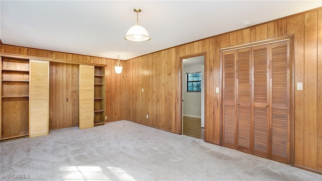 unfurnished bedroom with wood walls and light carpet