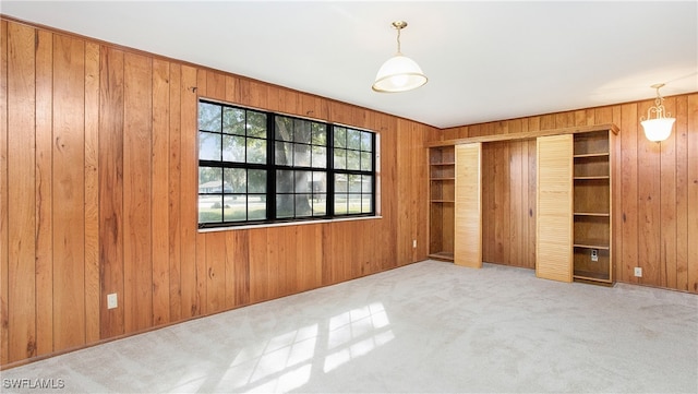 unfurnished bedroom with wood walls, light carpet, and a closet