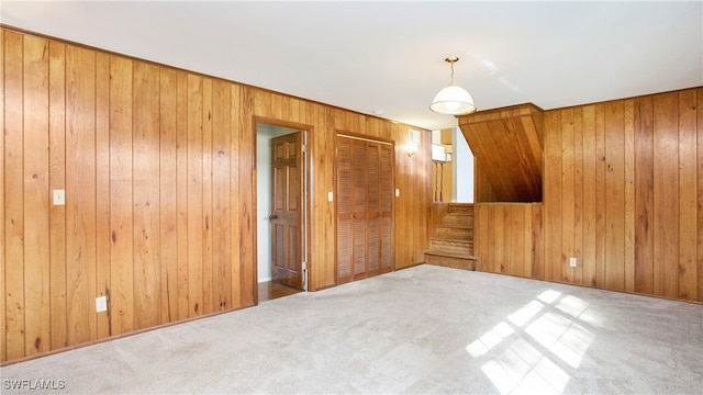 carpeted spare room featuring wood walls