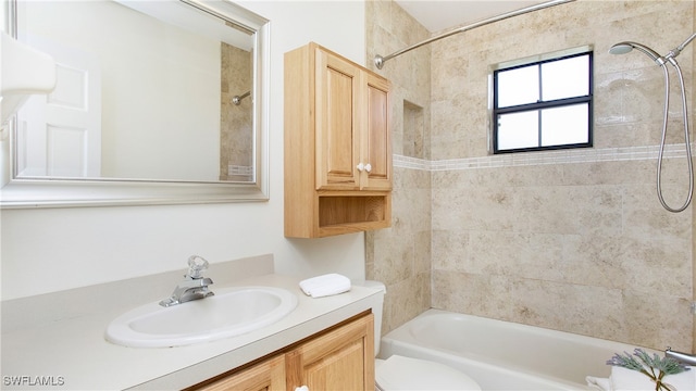 full bathroom featuring vanity, tiled shower / bath combo, and toilet