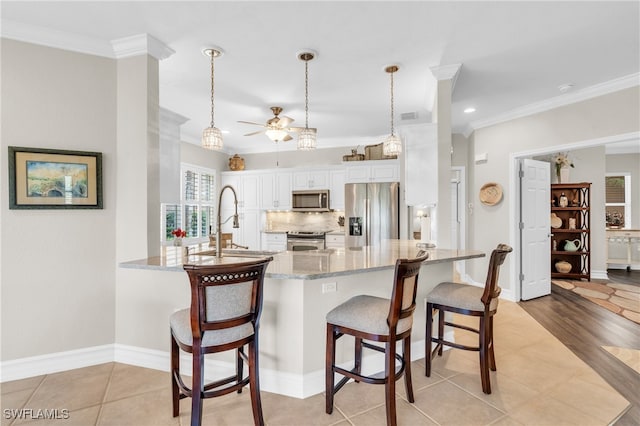 kitchen with kitchen peninsula, white cabinets, ornamental molding, pendant lighting, and stainless steel appliances