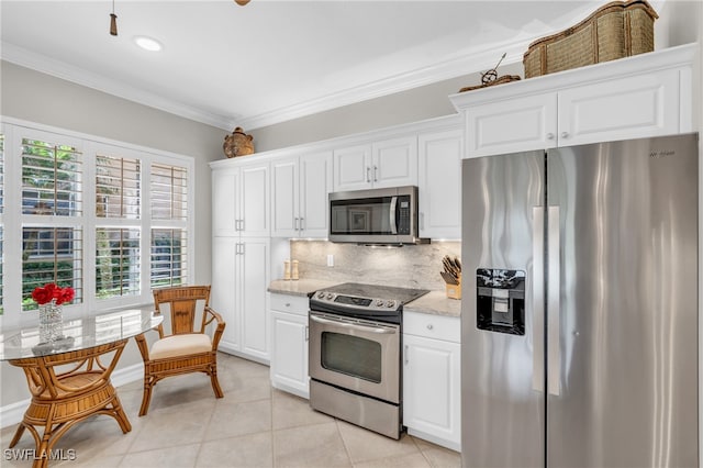 kitchen with a healthy amount of sunlight, appliances with stainless steel finishes, light stone countertops, and white cabinetry