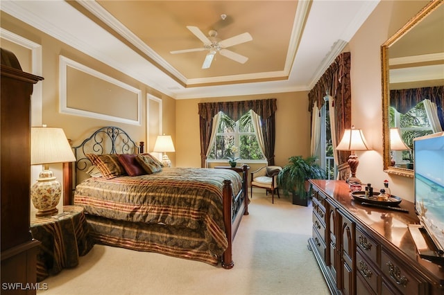 bedroom with ceiling fan, light colored carpet, a raised ceiling, and crown molding