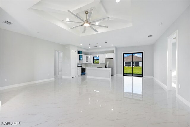 unfurnished living room with a tray ceiling and ceiling fan