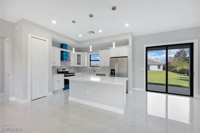 kitchen featuring decorative backsplash, stainless steel appliances, a center island, decorative light fixtures, and white cabinetry