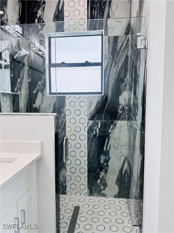 bathroom featuring a shower with door and vanity