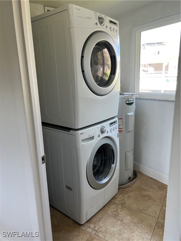 washroom featuring water heater, light tile patterned floors, and stacked washer and dryer