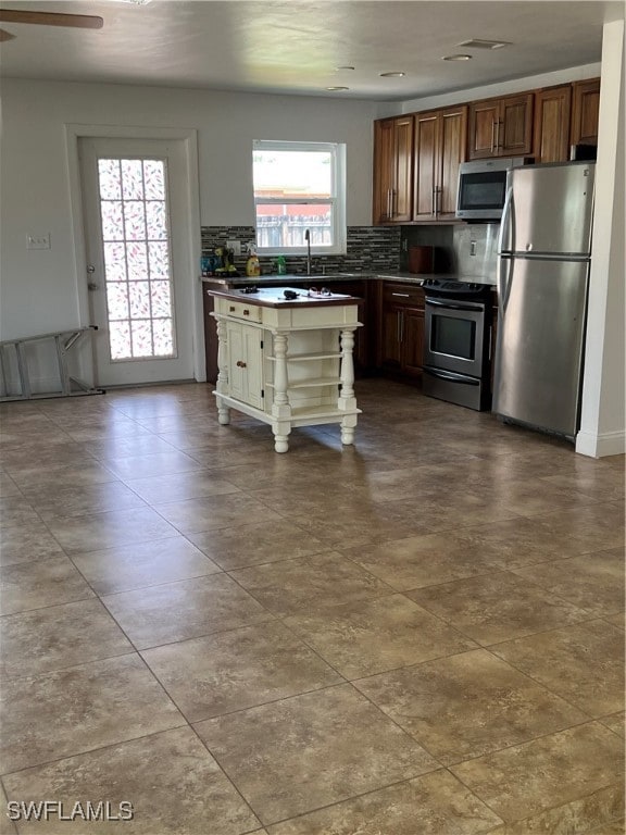 kitchen featuring backsplash, ceiling fan, a healthy amount of sunlight, and stainless steel appliances