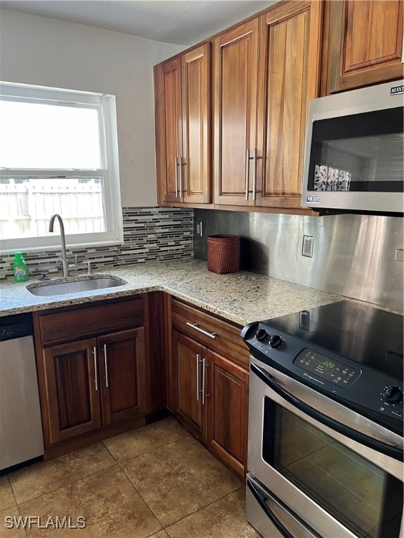 kitchen featuring light tile patterned floors, sink, backsplash, light stone countertops, and appliances with stainless steel finishes