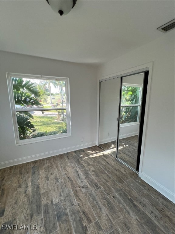 unfurnished room featuring plenty of natural light and dark hardwood / wood-style flooring