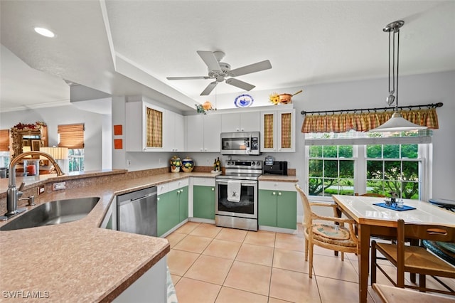 kitchen featuring hanging light fixtures, white cabinetry, sink, stainless steel appliances, and green cabinetry