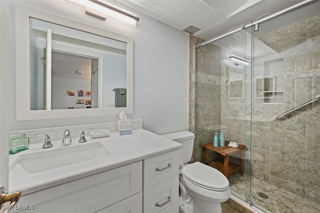 bathroom featuring vanity, a shower with shower door, a textured ceiling, and toilet