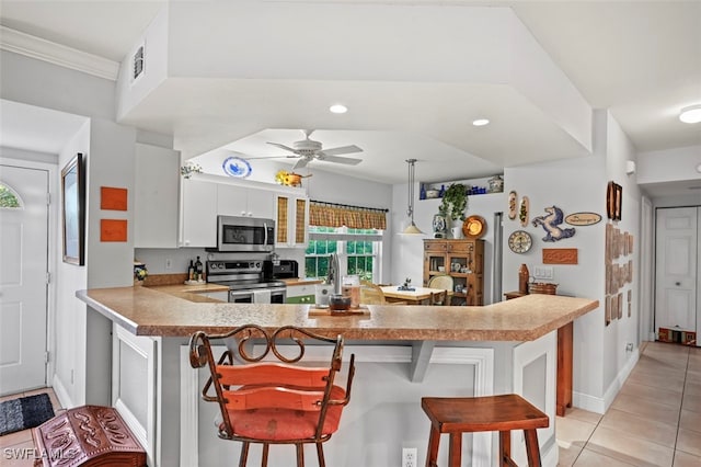 kitchen featuring appliances with stainless steel finishes, kitchen peninsula, hanging light fixtures, white cabinets, and a breakfast bar area