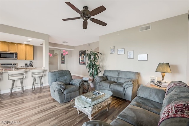 living room featuring ceiling fan and light hardwood / wood-style flooring