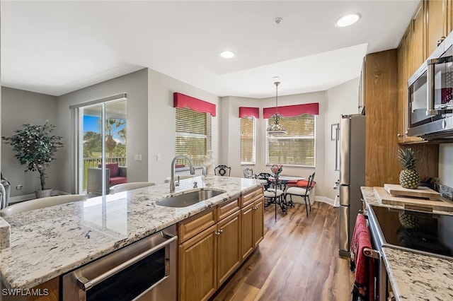 kitchen featuring a center island with sink, dark hardwood / wood-style flooring, sink, pendant lighting, and stainless steel appliances