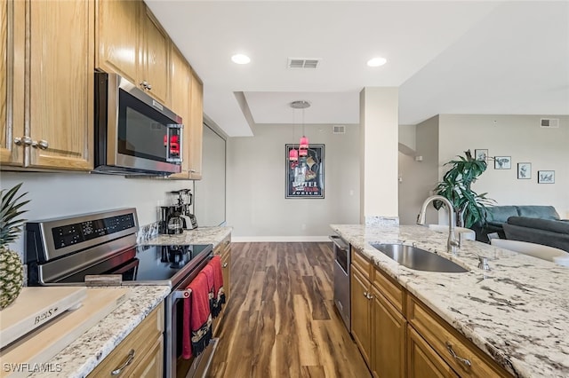 kitchen featuring light stone countertops, appliances with stainless steel finishes, sink, pendant lighting, and dark hardwood / wood-style floors