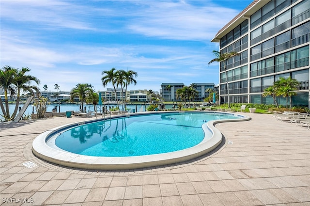 view of swimming pool featuring a patio and a water view