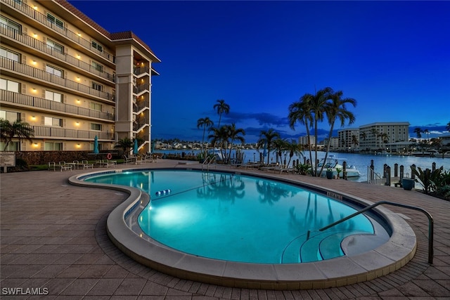 view of swimming pool with a water view and a patio area