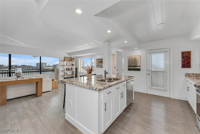 kitchen featuring white cabinetry, sink, light stone counters, an island with sink, and appliances with stainless steel finishes