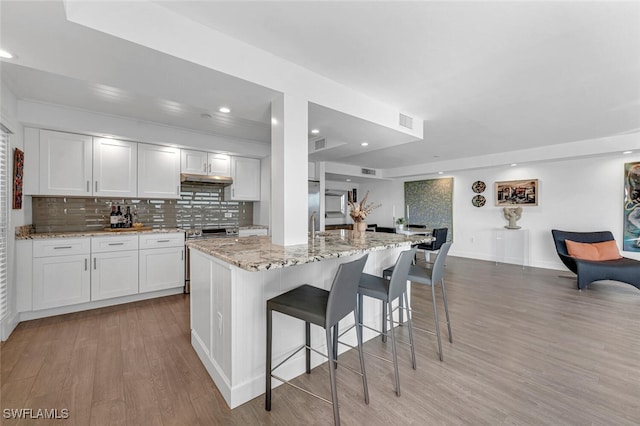 kitchen featuring white cabinets, a center island, light hardwood / wood-style flooring, and light stone counters