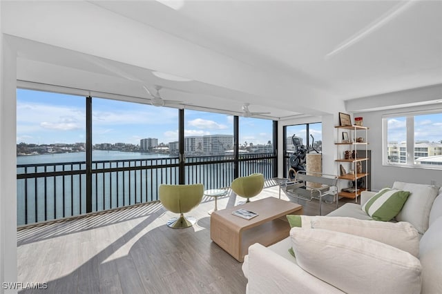 living room featuring ceiling fan, hardwood / wood-style floors, and a water view