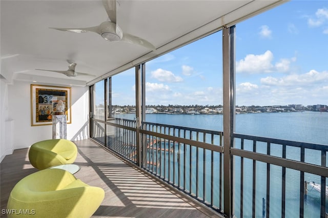 sunroom with ceiling fan and a water view