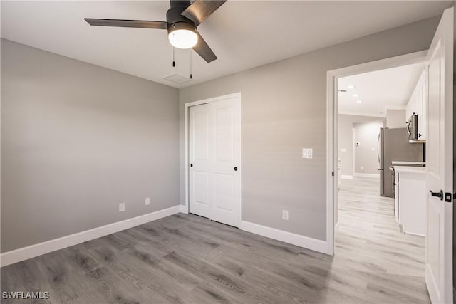 unfurnished bedroom with a closet, light wood-style flooring, and baseboards