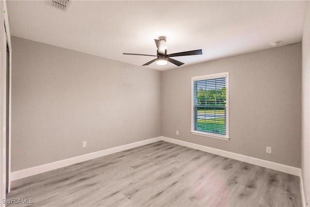 empty room with light wood-style floors, visible vents, baseboards, and a ceiling fan