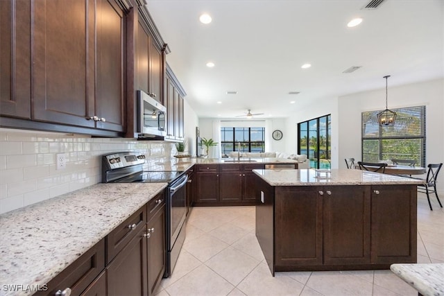 kitchen with hanging light fixtures, stainless steel appliances, light tile patterned floors, light stone counters, and tasteful backsplash