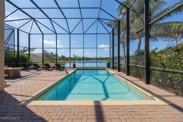 view of pool featuring a patio, a water view, and glass enclosure