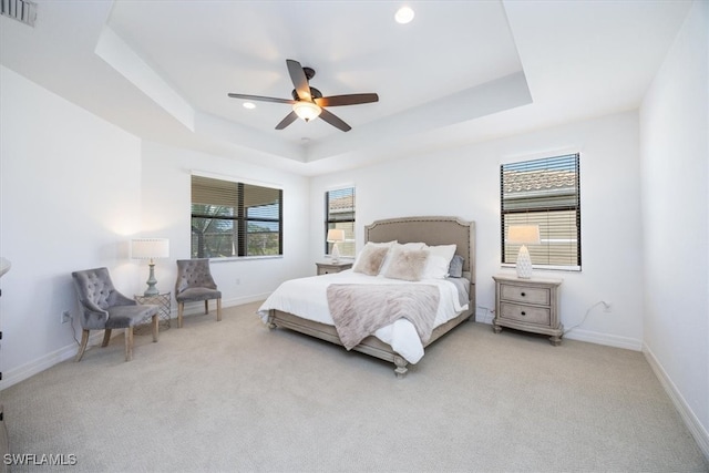 bedroom with ceiling fan, light carpet, and a raised ceiling