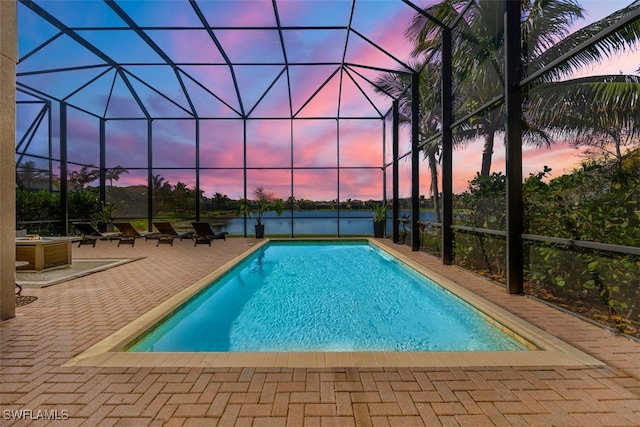 pool at dusk featuring a patio and glass enclosure