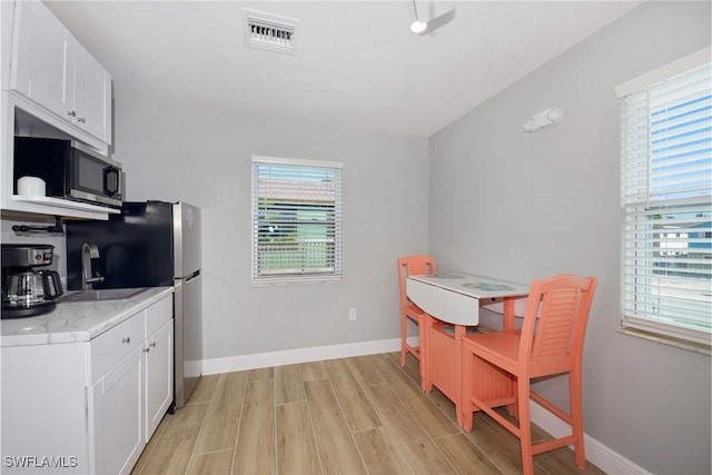 kitchen featuring white cabinets, light hardwood / wood-style floors, light stone countertops, and sink