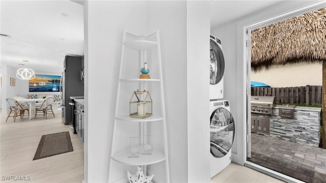 clothes washing area featuring light tile patterned floors and stacked washer and clothes dryer