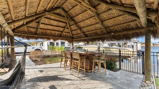 view of patio / terrace featuring a bar, a gazebo, and a water view