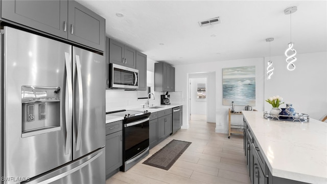 kitchen featuring appliances with stainless steel finishes, sink, hanging light fixtures, and gray cabinets