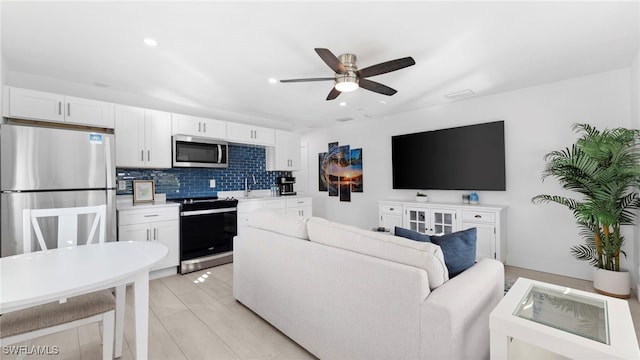 living room featuring light wood-type flooring, ceiling fan, and sink