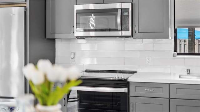 kitchen featuring gray cabinets, stainless steel appliances, and tasteful backsplash