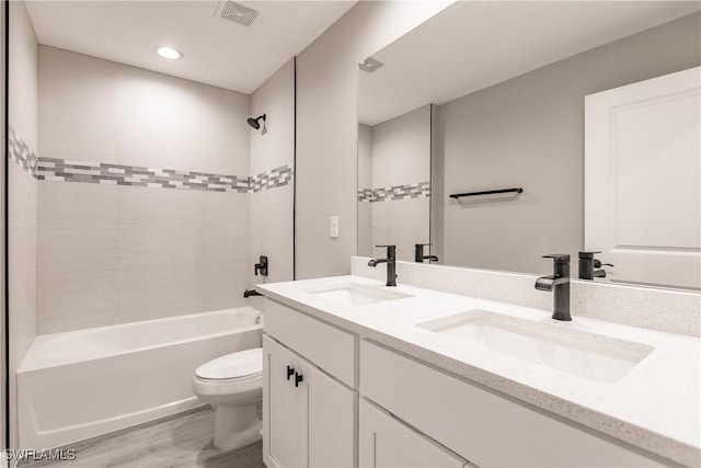 full bathroom with tiled shower / bath, hardwood / wood-style floors, vanity, and toilet