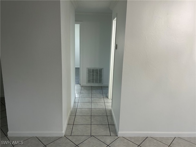 hallway with ornamental molding and light tile patterned floors