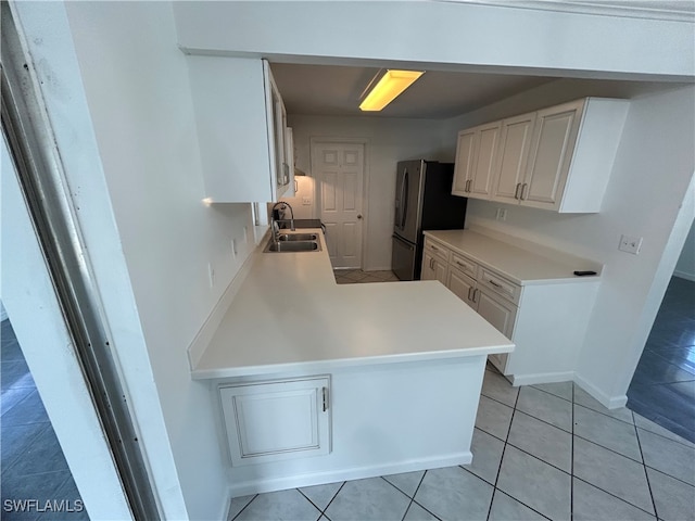 kitchen featuring kitchen peninsula, sink, light tile patterned floors, and stainless steel refrigerator