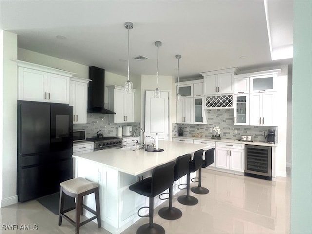 kitchen with wall chimney range hood, stainless steel appliances, wine cooler, pendant lighting, and white cabinetry