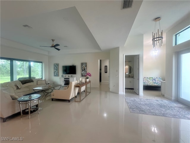 living room with light tile patterned flooring and ceiling fan with notable chandelier