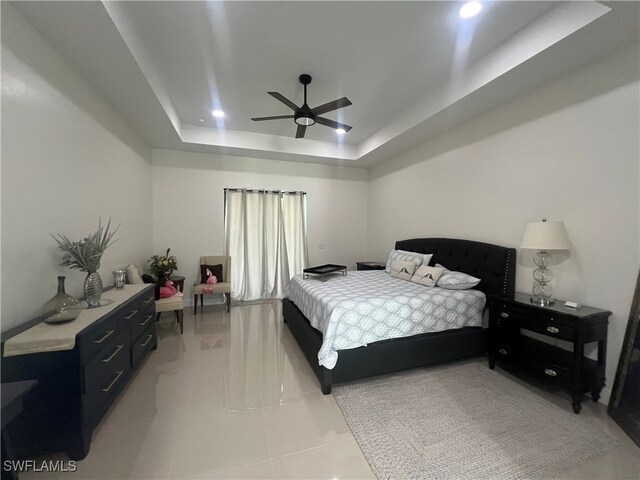 tiled bedroom featuring a raised ceiling and ceiling fan